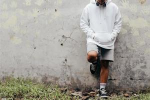 Mockup of a Man Wearing a Pullover Hoodie standing and laying on cement wall photo