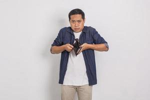 retrato de un hombre asiático triste y apuesto que muestra el contenido de su billetera aislado de fondo blanco foto