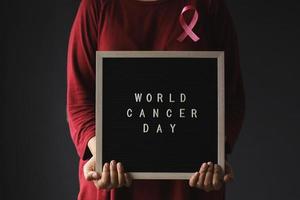 mujer con cinta rosa y tablero de mensajes para el día mundial del cáncer y la concienciación sobre el cáncer de mama foto