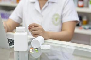 Pharmacist with laptop computer and medication in the pharmacy photo