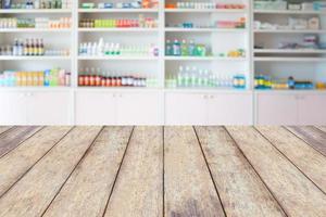 Mostrador de madera de farmacia con estantes borrosos de medicamentos en la farmacia foto