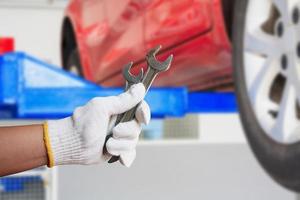 Car mechanic holding wrench at the car repair garage photo