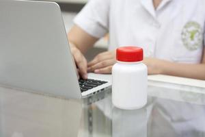 Pharmacist with laptop computer and medication in the pharmacy photo