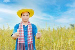 Asian peasants in robes and hats are in a field of golden rice fields. photo