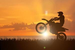 silueta de una moto de motocross levantando la rueda delantera. conceptos de aventura y acción foto