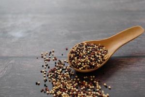 semillas de quinua en la cuchara de madera sobre fondo de mesa de madera. la quinua es una buena fuente de proteínas para las personas que siguen una dieta basada en plantas. foto