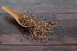 semillas de quinua en la cuchara de madera sobre fondo de mesa de madera. la quinua es una buena fuente de proteínas para las personas que siguen una dieta basada en plantas. foto