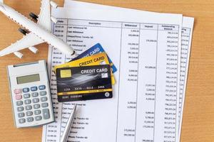 modelo de avión y calculadora en extracto bancario y tarjeta de crédito en una mesa de madera. finanzas sobre el concepto de viaje foto