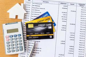 House model and calculator on Bank statement and credit card on a Wooden table. home purchase mortgage concept photo