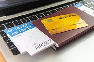 tarjeta de crédito y pasaportes cerca de la computadora portátil en la mesa. concepto de reserva de boletos en línea foto
