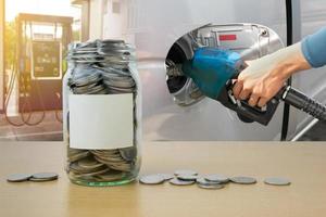 botella de dinero con monedas, mano sosteniendo boquilla de combustible vertiendo fondo foto