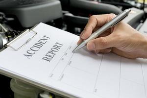 Mechanic Inspecting damage car and filling in accident report form photo