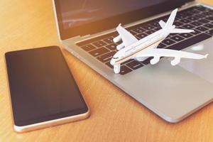 Smartphone near laptop computer and airplane on table. Online ticket booking concept photo