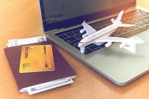 boletos aéreos, pasaportes y tarjetas de crédito cerca de la computadora portátil y el avión en la mesa. concepto de reserva de boletos en línea foto