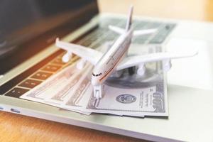 laptop computer and airplane and money on table. Online ticket booking concept photo