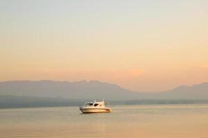 Beautiful Background with Ship at sunrise with golden clouds in Lake Toba