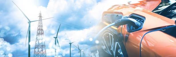 Electric EV car charge battery with wind turbine pole and blue sky blur bokeh on panoramic background. Idea nature electric energy to generate electricity. Green energy eco concept.