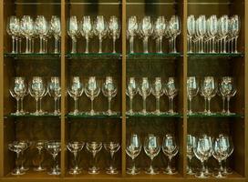 Set of glasses for different alcoholic drinks and cocktails on wood shelf background. photo