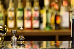 black marble table top and beautiful bokeh shelves with alcohol bottles photo