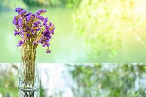 las flores violetas secas para la decoración están en un jarrón sobre una mesa de cristal foto