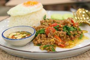 Stir fried Thai basil with minced pork and a fried egg on white plate photo