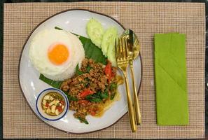 Stir fried Thai basil with minced pork and a fried egg on white plate photo