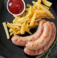 Chicken sausages grilled with a side dish of  french fries photo