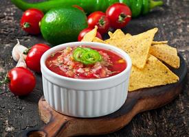 Mexican nacho chips and salsa dip in  bowl on  wooden background photo