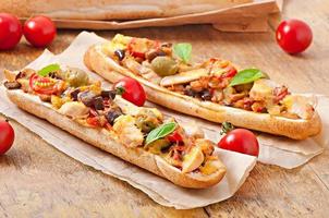 Big sandwich with roasted vegetables  and chicken with cheese and basil on old wooden background photo