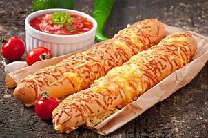 Salsa dip in bowl of bread and cheese sticks on wooden background photo