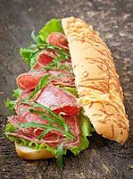 Sandwich with salami, lettuce, tomato and arugula photo