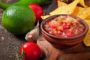 Mexican nacho chips and salsa dip in  bowl on  wooden background