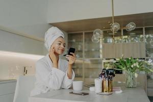 Happy healthy woman in bathrobe taking care of her skin after taking shower or bath at home photo