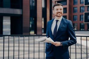 Happy office worker on break standing while holding newspaper photo