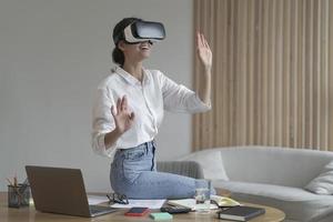 Businesswoman in elegant formal clothes sitting in office and using VR technologies at work