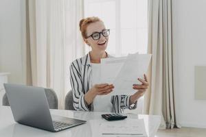 Cheerful professional accountant prepares annual financial report looks at documents photo