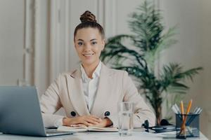 Cheerful business lady in elegant clothes smiling pleasantly at camera photo