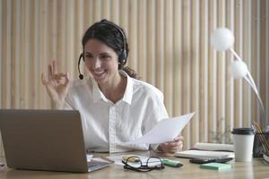 Smiling Italian business woman in white shirt participating in business meeting video conference
