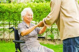 Asian elderly woman disability patient sitting on wheelchair in park, medical concept. photo