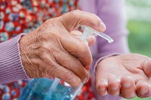 mujer mayor asiática presione gel desinfectante de alcohol azul para lavarse las manos proteger la infección por coronavirus. foto