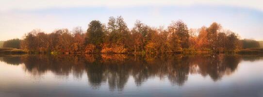 Forest autumn panorama above the water trees are reflected in the surface of the water photo