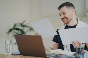 Happy entrepreneur looking at documents while working at home office photo