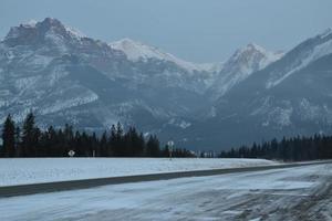 Snow covered highway with mountains in the background photo