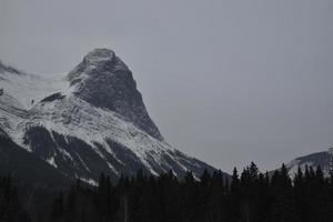 Snow Covered Rocky Mountains with Hazy Grey Sky photo