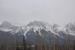 Snow Covered Rocky Mountains with Hazy Grey Sky photo