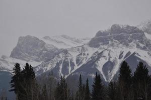 Snow Covered Rocky Mountains with Hazy Grey Sky photo