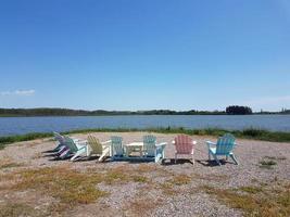 Pink, Blue and Yellow Deck chairs on a Lake shore photo