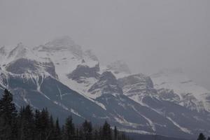 Snow Covered Rocky Mountains with Hazy Grey Sky photo