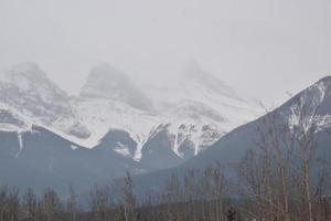 Snow Covered Rocky Mountains with Hazy Grey Sky photo