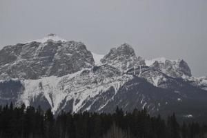 Snow Covered Rocky Mountains with Hazy Grey Sky photo